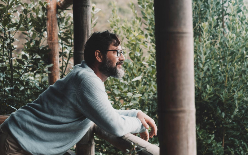 Uomo che osserva il paesaggio in un momento di quiete e presenza mentre riflette sul cambiamento che emerge quando la pressione interna diminuisce