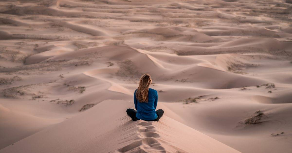 Immagine di ragazza seduta sulla sabbia del deserto. - Che rapporto hai con i tuoi pensieri