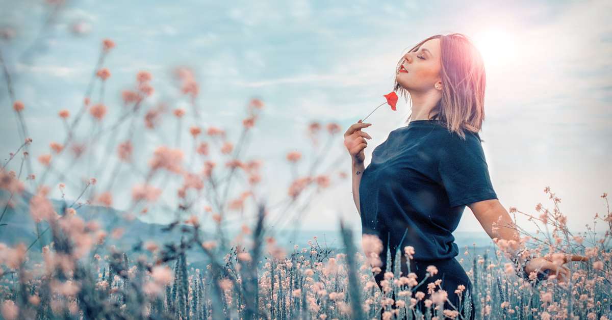 Consapevolezza e gestione dello stress - Donna felice in mezzo ai fiori