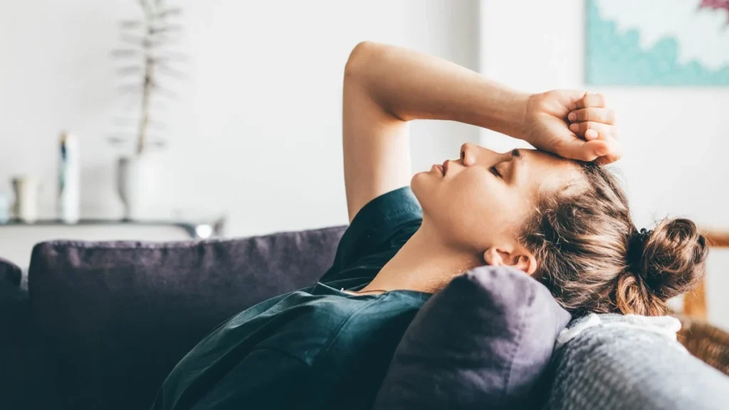persona stanca sul divano affaticamento e tensione nel corpo